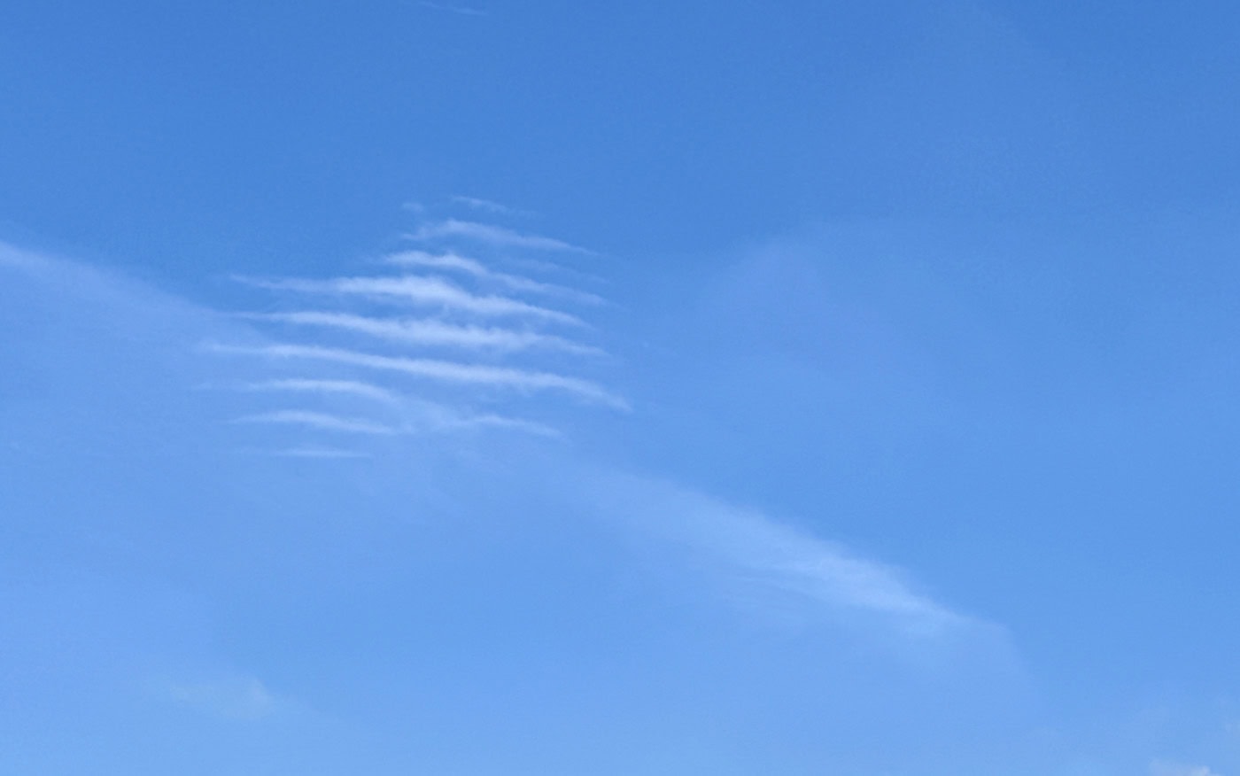a series of small thin separate ripples of cloud in a blue sky